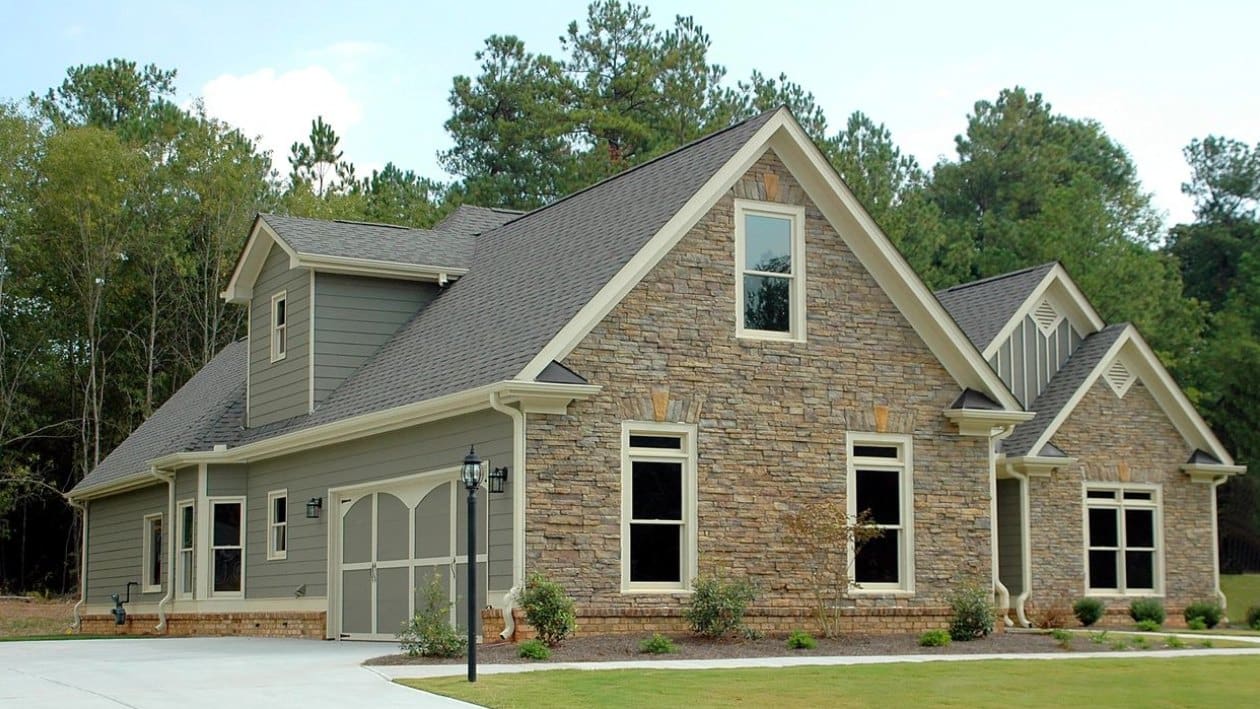 A large brick house with a green lawn.