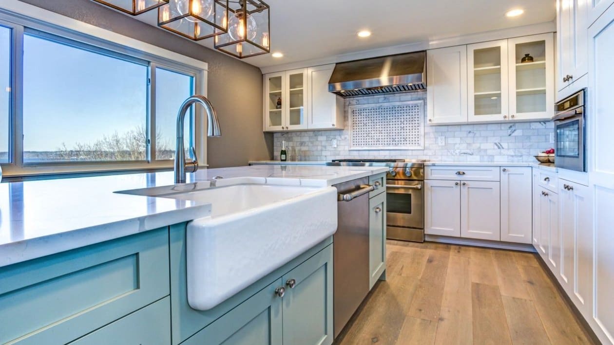 A kitchen with white cabinets and a large sink.