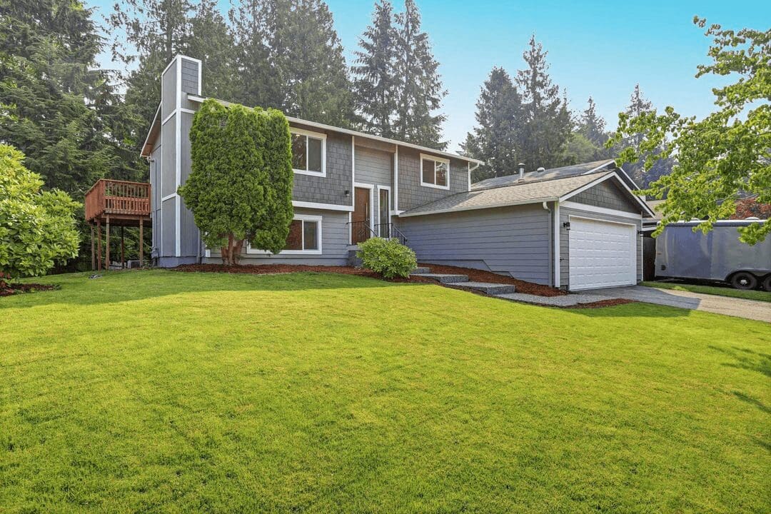 A house with a large yard and trees in the background.